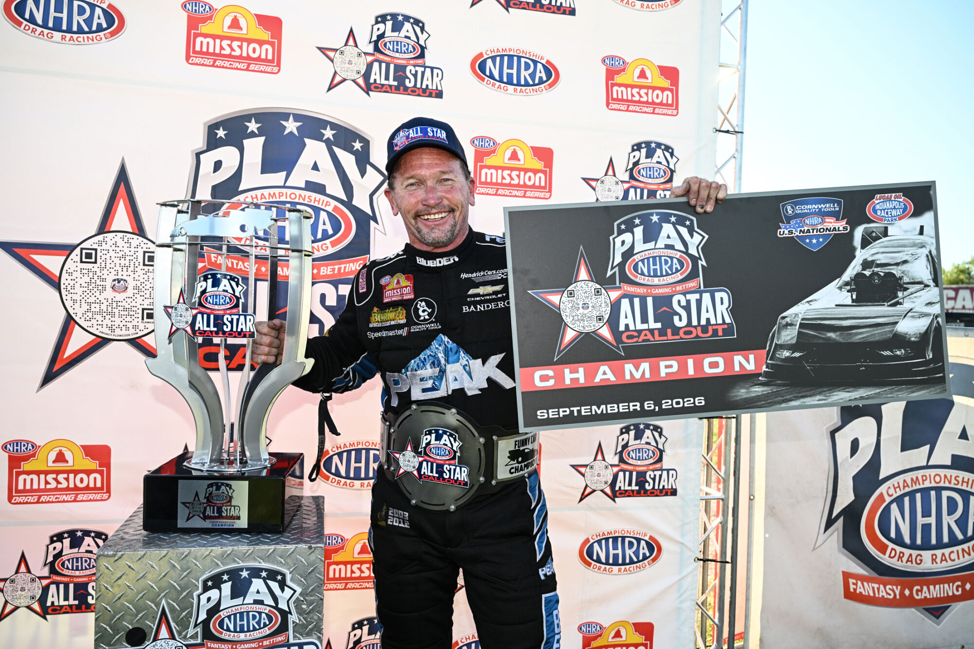 Jack Beckman holds the NHRA All-Star Callout championship trophy, belt and winner banner at Lucas Oil Indianapolis Raceway Park