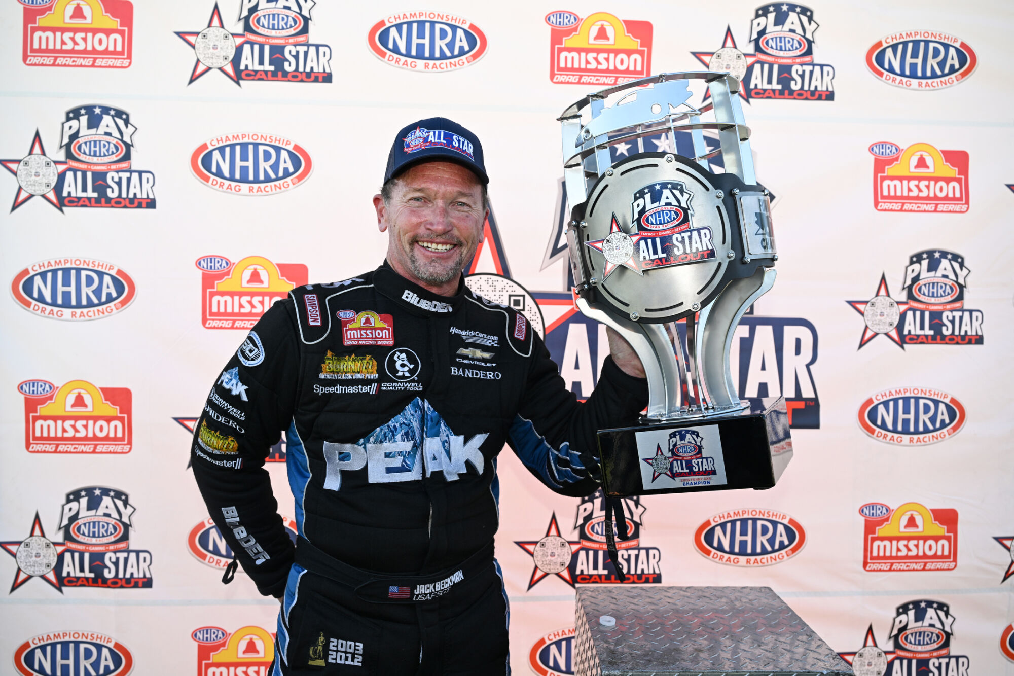 Jack Beckman holds the NHRA All-Star Callout trophy in front of the event backdrop at Indianapolis