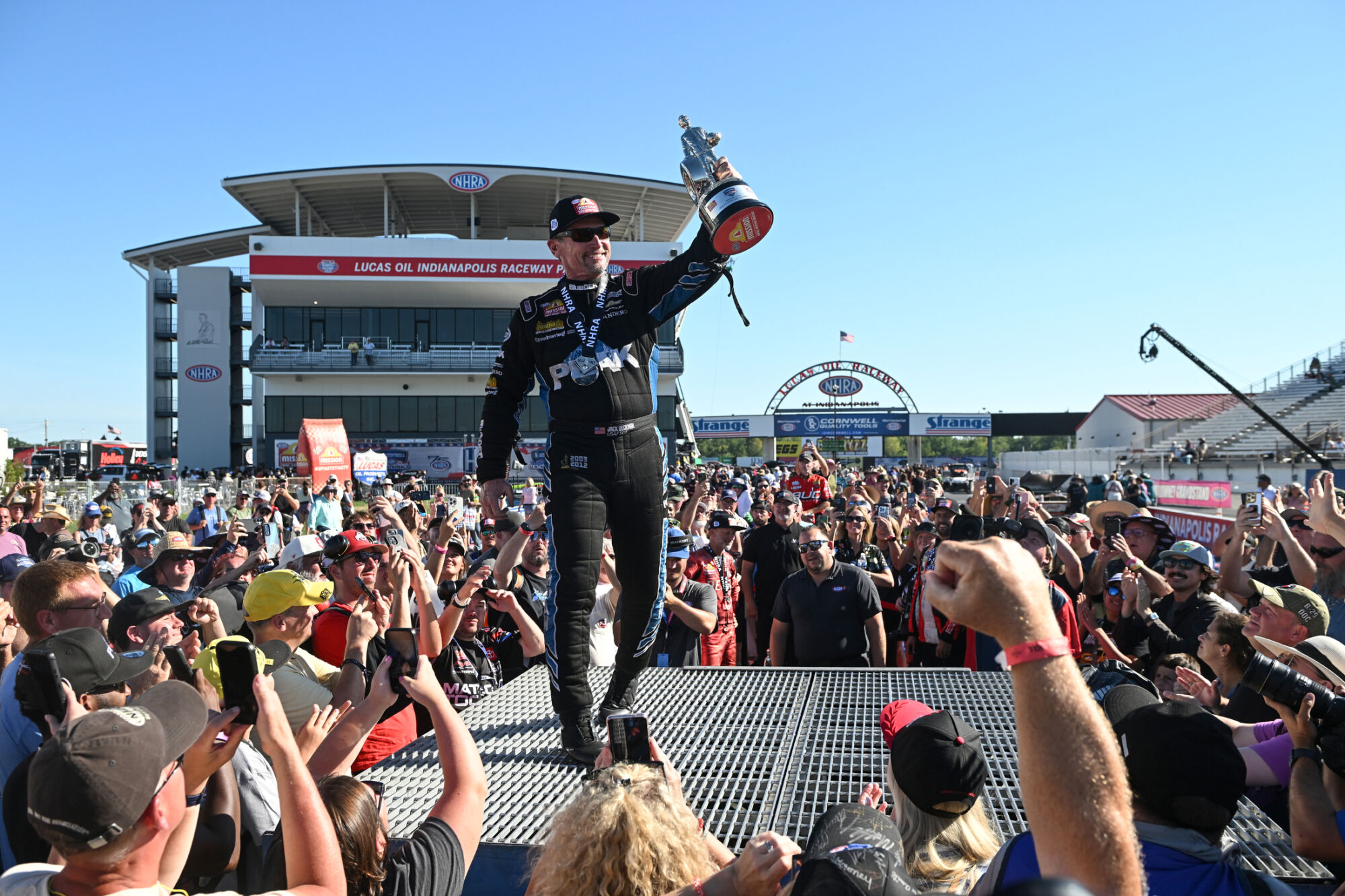Jack Beckman holds the Wally on the winners stand surrounded by fans at Lucas Oil Indianapolis Raceway Park