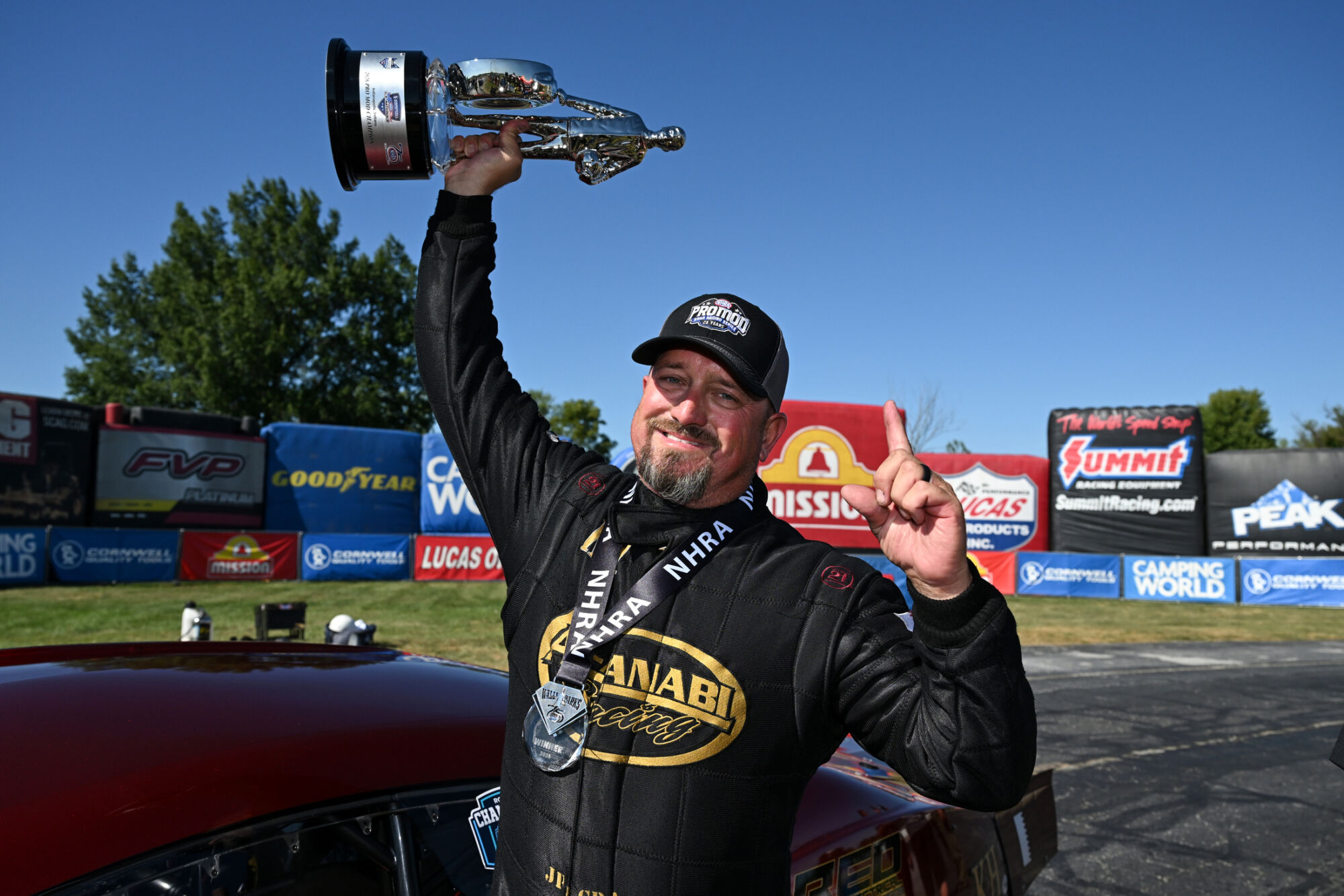 J.R. Gray raises the Wally trophy beside his Al-Anabi Racing Pro Mod at the 2026 NHRA U.S. Nationals