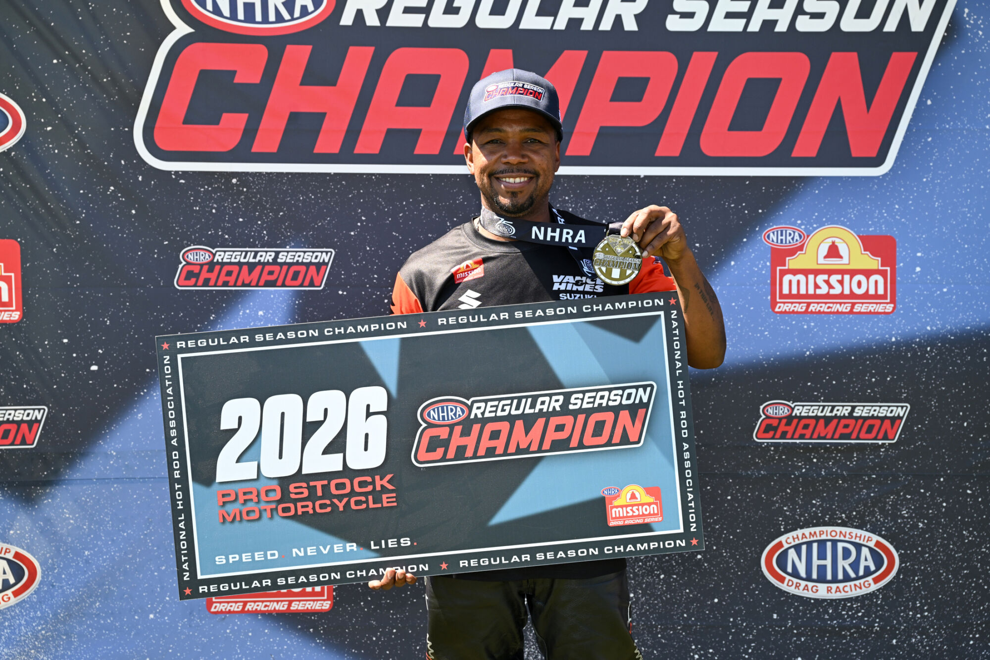 Richard Gadson holds the 2026 NHRA Pro Stock Motorcycle Regular Season Champion sign at Lucas Oil Indianapolis Raceway Park