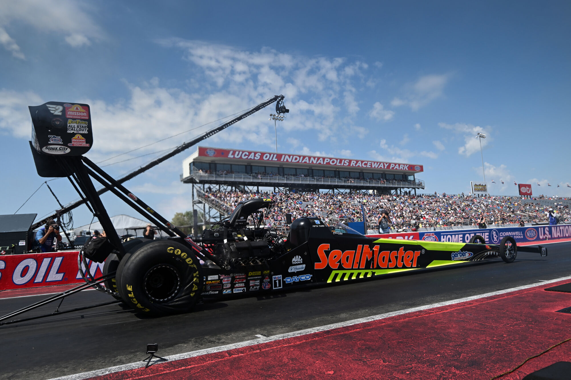 Shawn Langdon launches the SealMaster Top Fuel dragster off the starting line at Lucas Oil Indianapolis Raceway Park with the tower and grandstands behind him