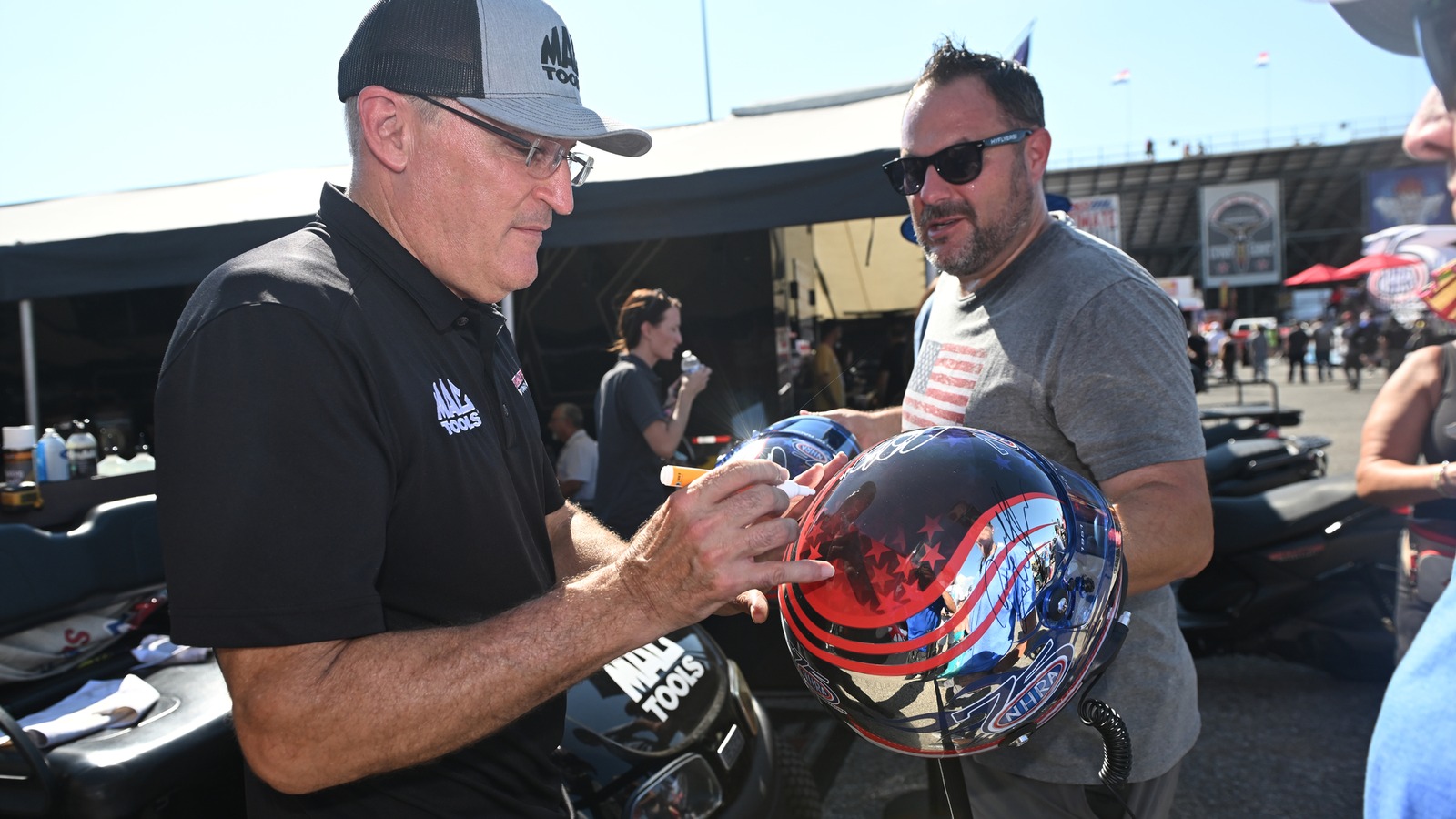 Top Fuel points leader Doug Kalitta signs a fan helmet in the pits at Lucas Oil Indianapolis Raceway Park