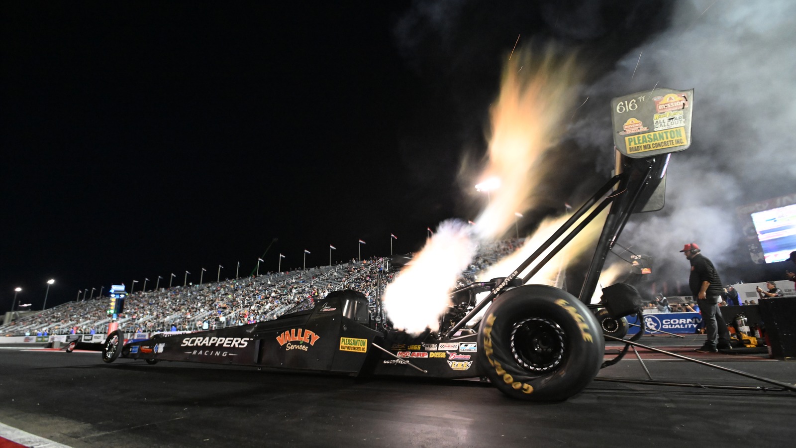 Jasmine Salinas launches her Scrappers Racing Top Fuel dragster under the lights at the NHRA U.S. Nationals, header flames lighting the starting line