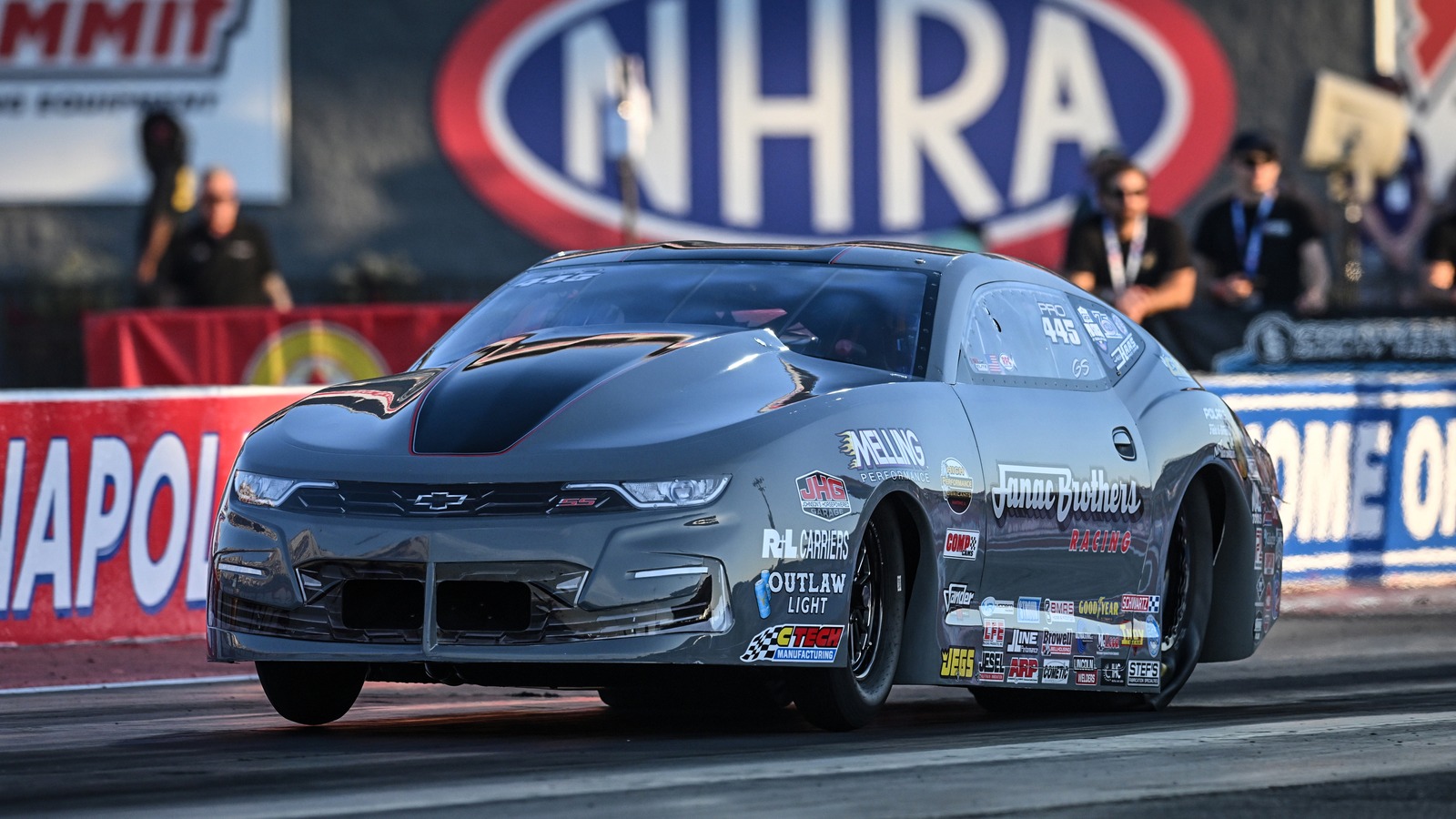 Greg Stanfield launches the grey Janac Brothers Racing Chevrolet Camaro Pro Stock car past the NHRA sign at Indianapolis
