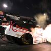 Jack Beckman launches the black and white PEAK John Force 16 time champion tribute Funny Car under the lights at Indianapolis, header flames lighting the starting line