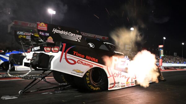 Jack Beckman launches the black and white PEAK John Force 16 time champion tribute Funny Car under the lights at Indianapolis, header flames lighting the starting line