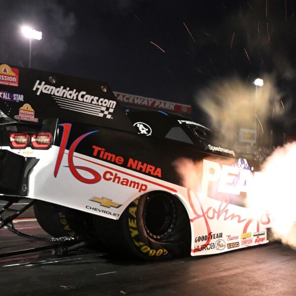 Jack Beckman launches the black and white PEAK John Force 16 time champion tribute Funny Car under the lights at Indianapolis, header flames lighting the starting line