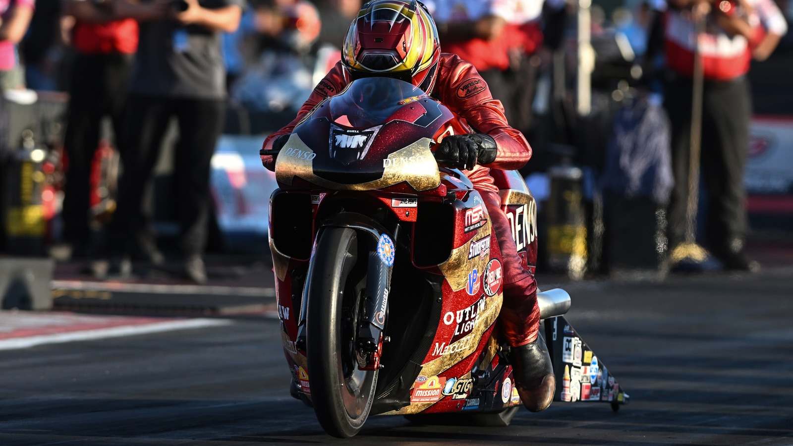 Matt Smith tucked in on the red and gold Denso Buell Pro Stock Motorcycle leaving the starting line at Indianapolis