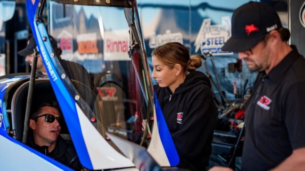 Aaron Stanfield sits in Leah Pruett's Tony Stewart Racing Top Fuel dragster as Pruett looks on at Texas Motorplex