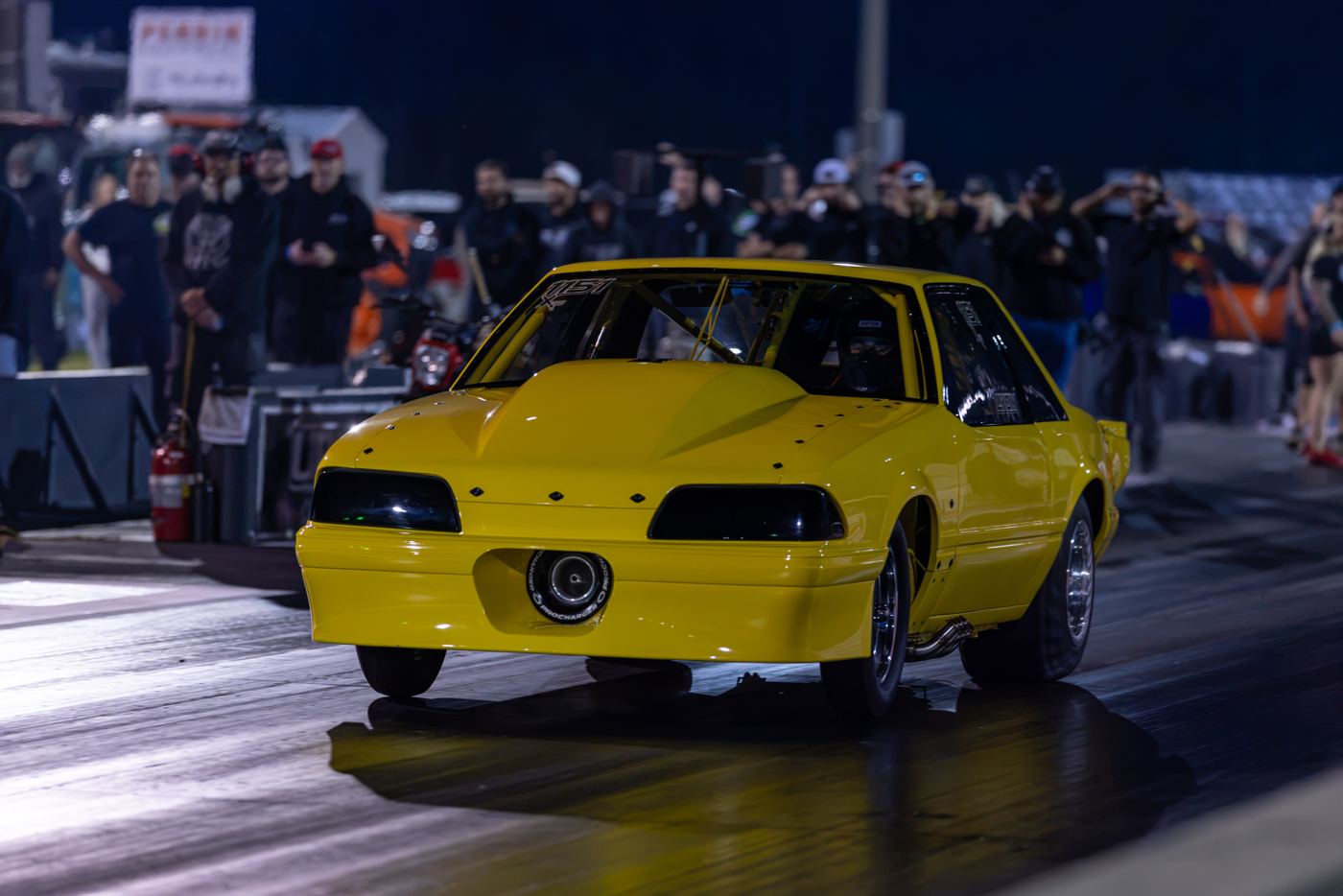 Yellow Fox-body Mustang stages in front of the crowd during Friday qualifying at No Mercy 17
